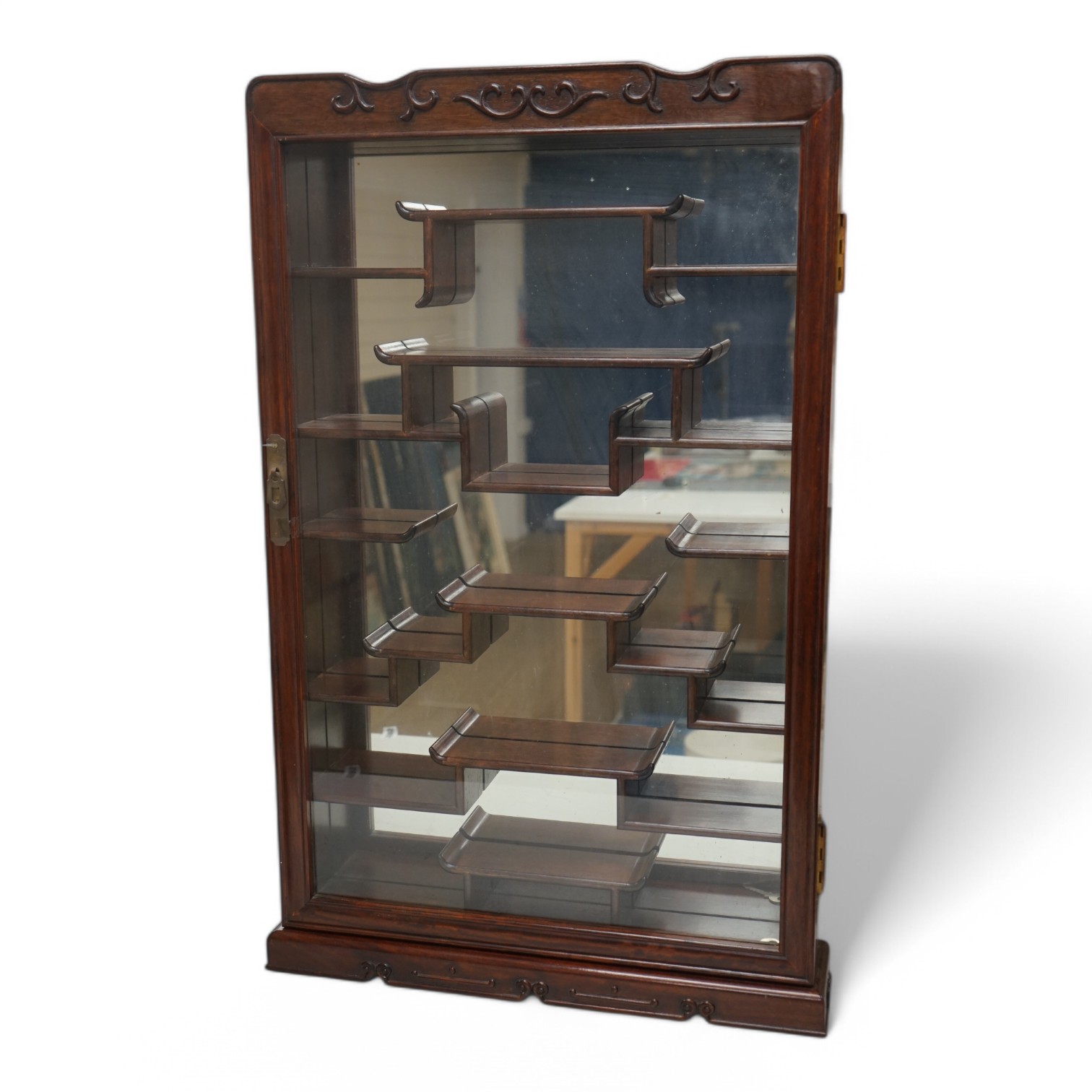 A narrow Chinese hardwood display cabinet, fitted with decorative shaped hardwood shelving, 82.5cm high x 53cm wide at base x 10.5cm deep at base. Condition - marks to wood when cello tape has been, other wise good